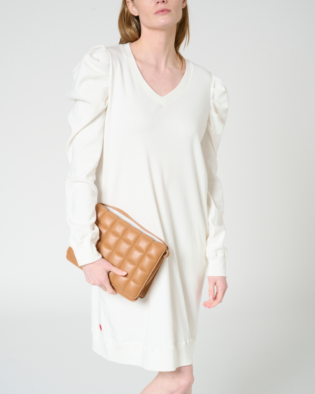 Woman wearing puff sleeve white dress holding clutch